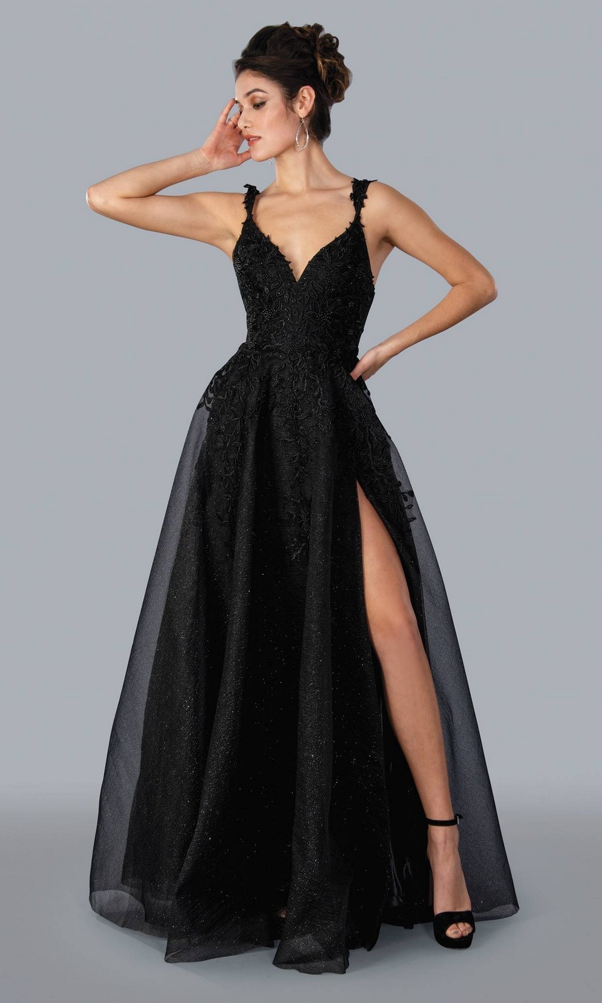 A woman models the Embroidered-Lace Long A-Line Prom Ball Gown 20058—a sleeveless black glitter dress with a deep V-neck, embellished bodice, high slit, and sheer overlay—standing before a plain gray background.
